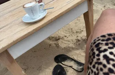Alleinreisende Person plant eine Reise am Laptop neben Karte und Koffer